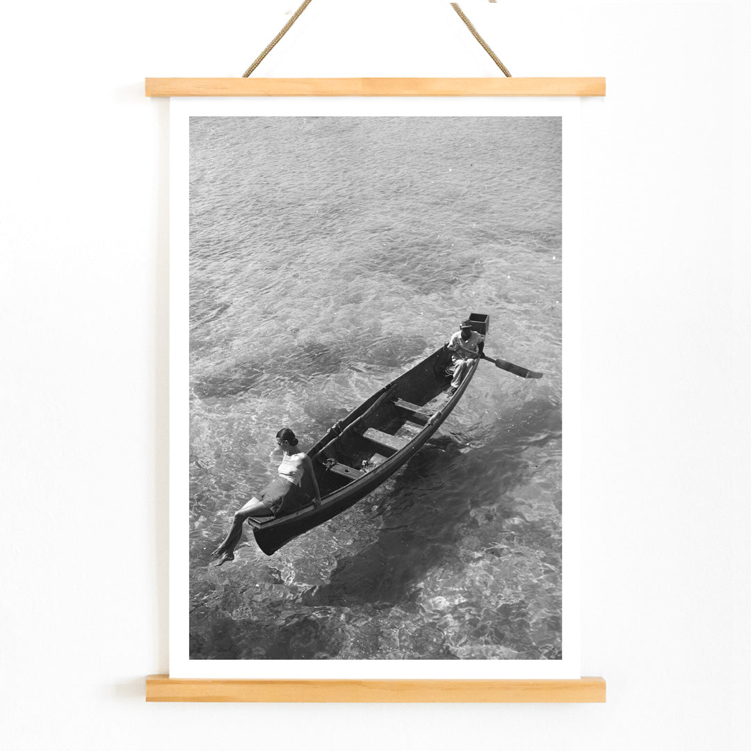 Fashion model on boat edge with man rowing in clear water Montego Bay Jamaica by Toni Frissell artwork poster, with wooden magnetic frame on white background