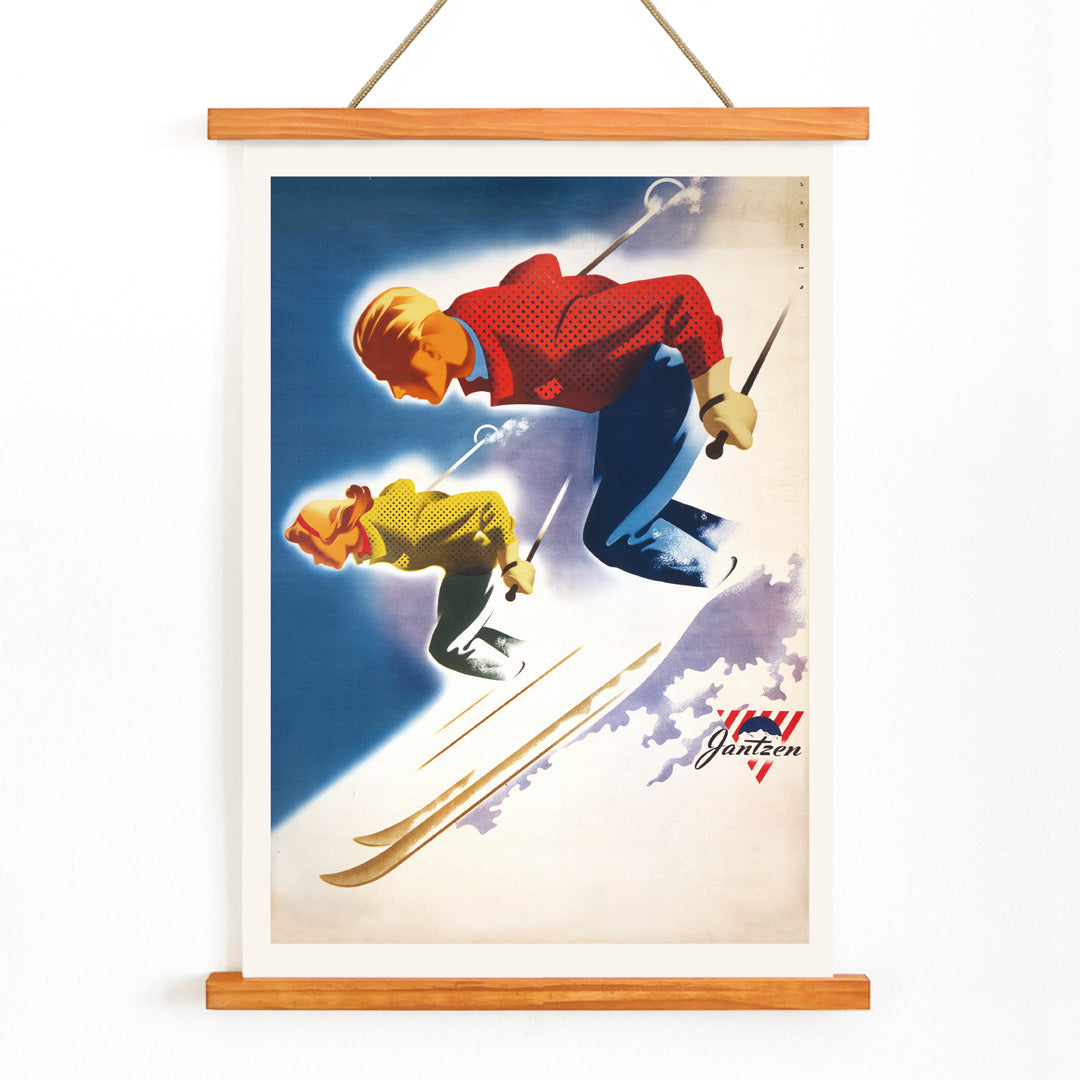 Vintage skiing poster of man and woman skiing downhill in bold colors by Joseph Binder for Jantzen, with wooden magnetic frame on white background