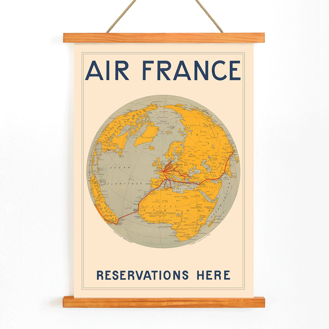 Vintage Air France travel poster by E Giraud showing world map with airline routes highlighted in red, with wooden magnetic frame on white background