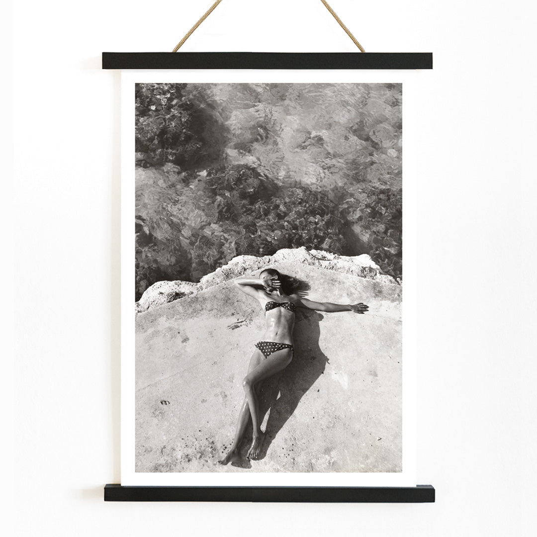 Woman in bikini lying on platform near water in Montego Bay Jamaica artwork by Nickerson Paine poster, with wooden magnetic frame on white background