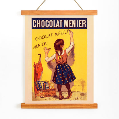 Chocolat Menier poster by Firmin Bouisset featuring a young girl writing on a yellow wall with a basket of chocolate and an umbrella, with wooden magnetic frame on white background