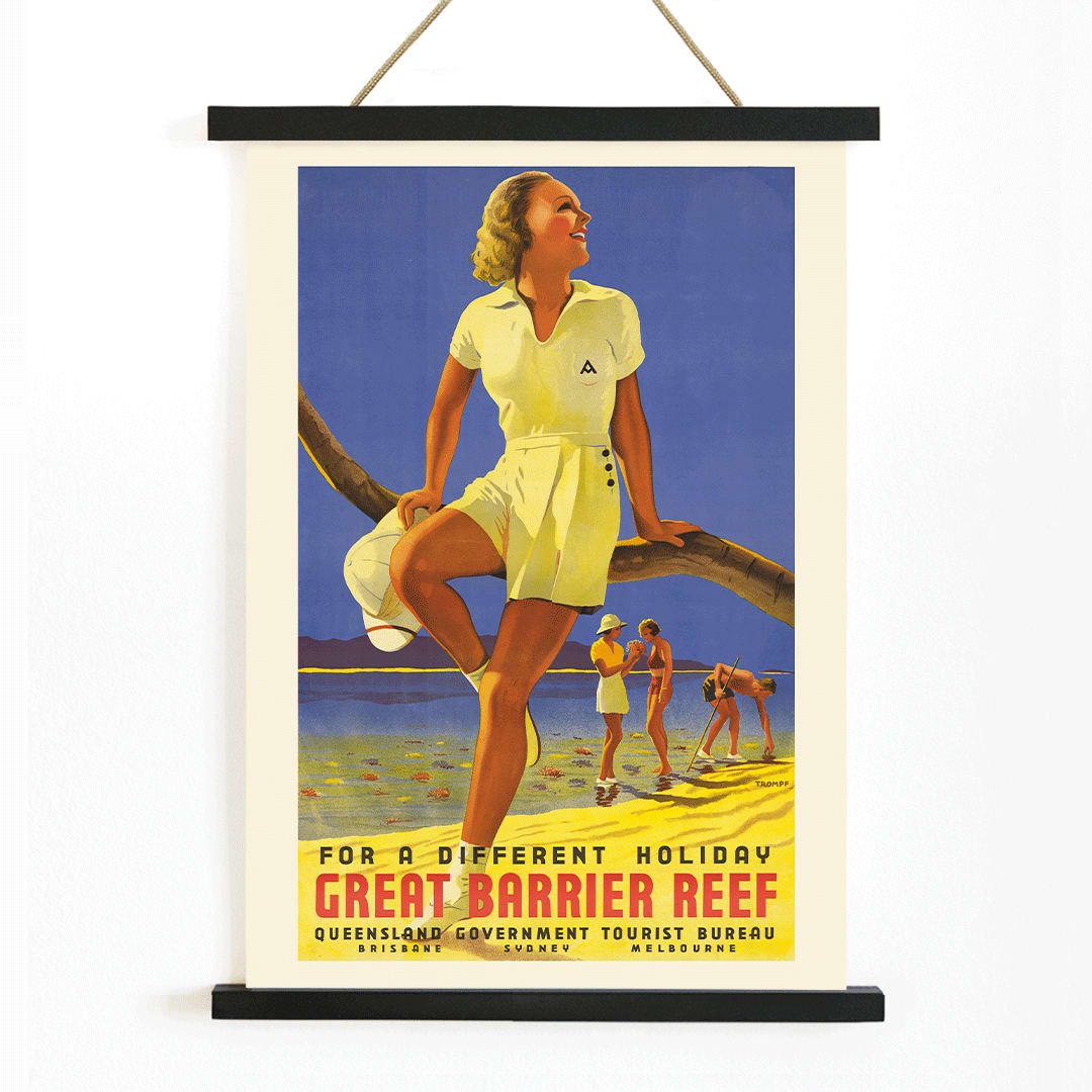 Vintage travel poster by Percival Albert Trompf showing a woman sitting on a branch at the Great Barrier Reef with people enjoying the beach in the background, with wooden magnetic frame on white background