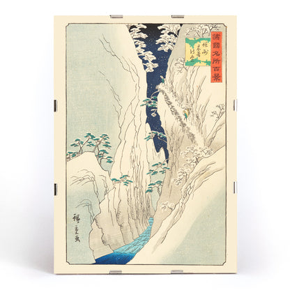 Snowy mountain gorge with river travelers and trees in The Kiso Gorge in Snow Shinano Province by Hiroshige II Japanese artwork poster, framed and displayed in modern living room decor