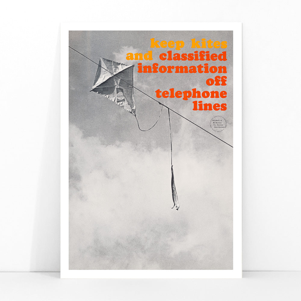 Black and white photo and poster of a kite tangled on a telephone line with bold warning text Keep kites and classified information off telephone lines, framed and displayed in modern living room decor