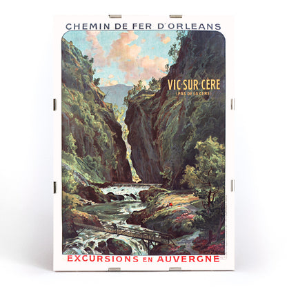 Scenic mountain gorge with river and footbridge in Vic Sur Cere travel poster by Louis Tauzin artwork for excursions in Auvergne, framed and displayed in modern living room decor