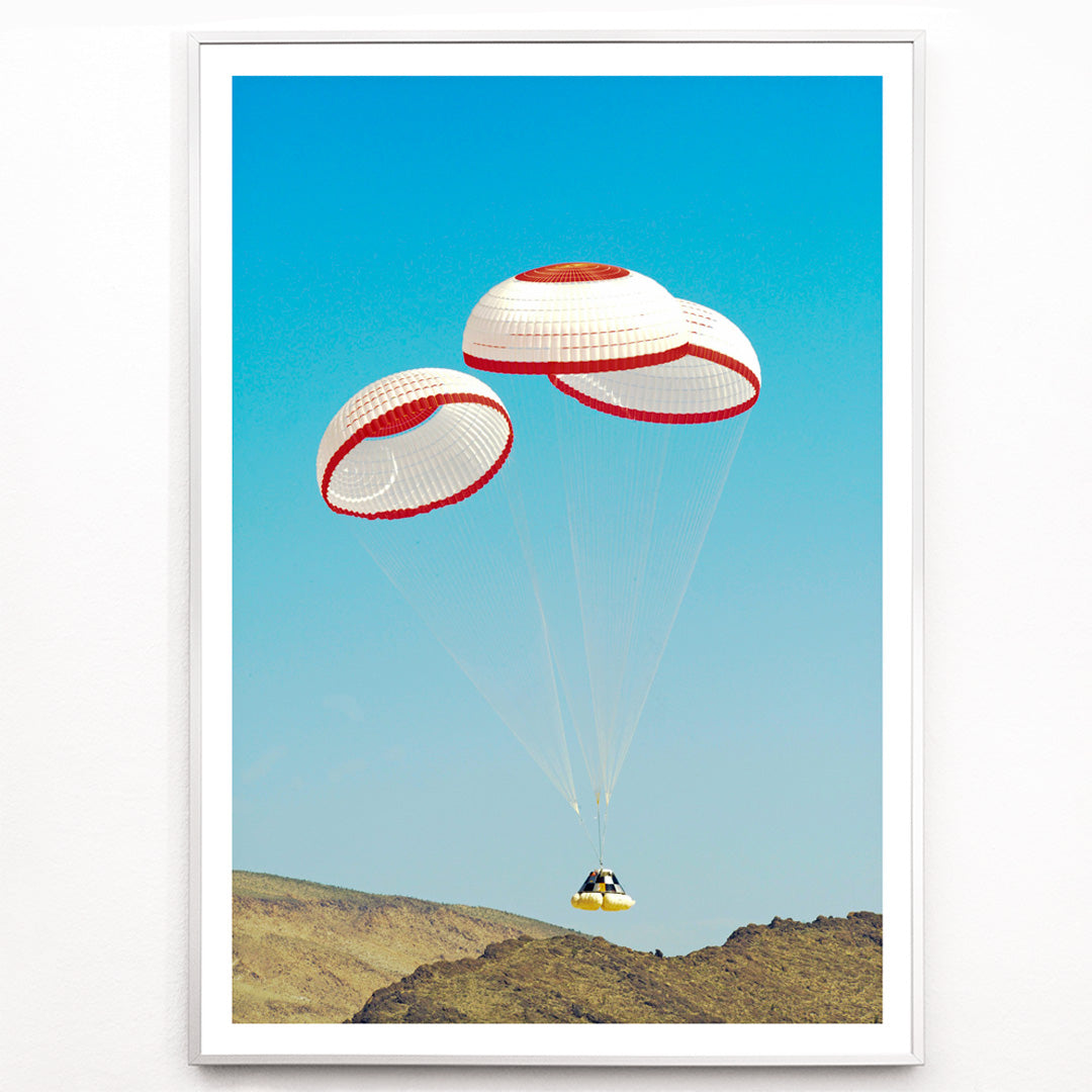 Closeup detail of CST-100 crew capsule landing with three parachutes over desert landscape by NASA and The Boeing Company poster artwork