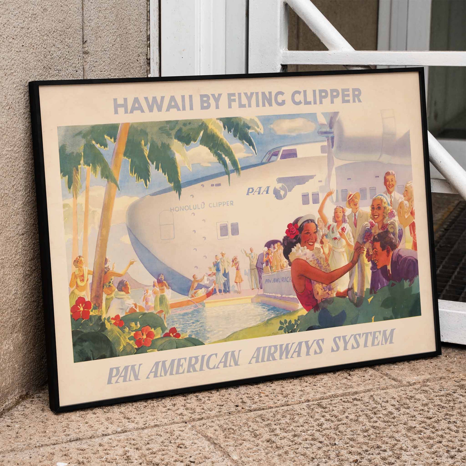 Vintage travel poster of Pan American Airways seaplane in Hawaii with people greeting each other with leis and Hawaiian welcome scene, framed and displayed in home decor