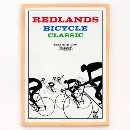 Cyclists racing illustration and poster by Karlis Smiltens titled Redlands Bicycle Classic featuring red blue and green text on white background, framed and displayed in modern living room decor