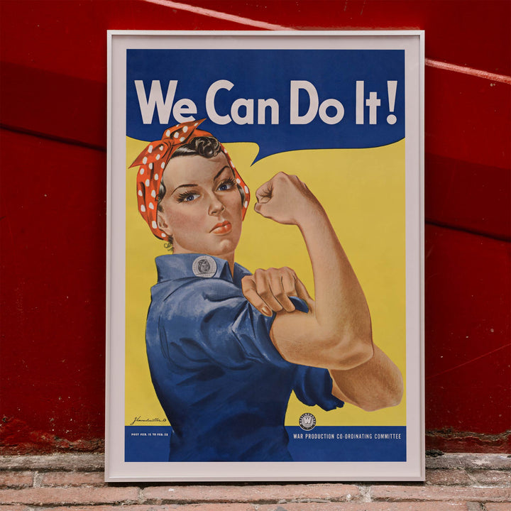 We Can Do It poster by J Howard Miller with determined woman flexing arm in blue and yellow wartime style, framed and displayed in home decor